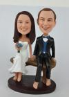 Custom wedding cake topper bobbleheads sitting on bench